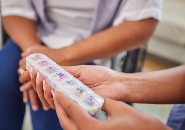 A person holding a medicines box marked with the days of the week. Image by PeopleImages.com YuriA via Shuterstock