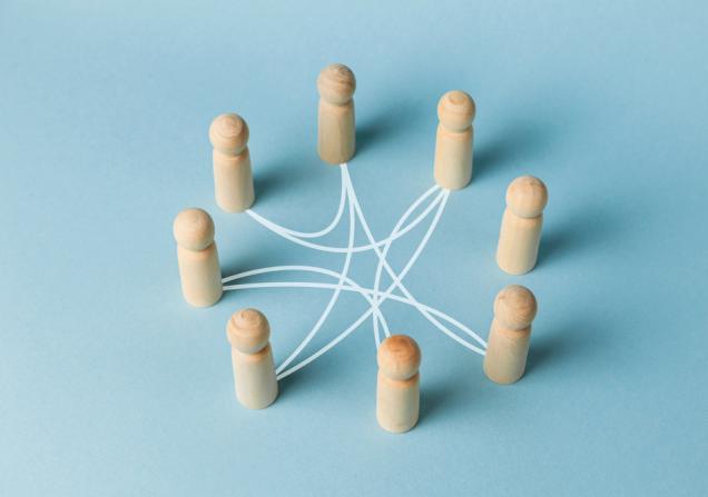 A circle of wooden figures connected by white lines, symbolising networking. Image via Shutterstock.