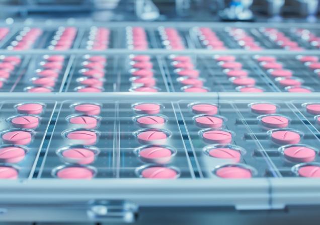 Pink pills rolling off the production line. Image by IM Imagery via Shutterstock.