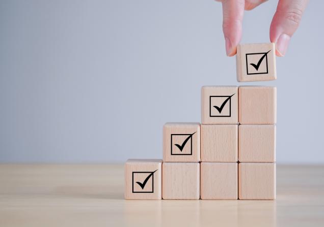 A set of wooden blocks, rising in height, with a tick at the top of each column to show regulatory approval of health research results.