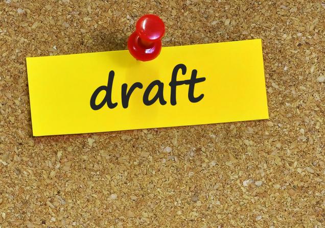 Draft written on yellow paper, pinned to a cork board, shows health research funding opportunities. Image by underverse, Shutterstock