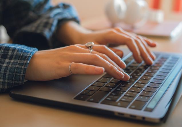 Close-up of a woman typing on a laptop. Image by mikesneaky via Shutterstock