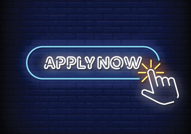 White neon lights say 'APPLY NOW' and a neon hand is clicking on this. The background is dark blue tiles. Image by bohlam via Shutterstock