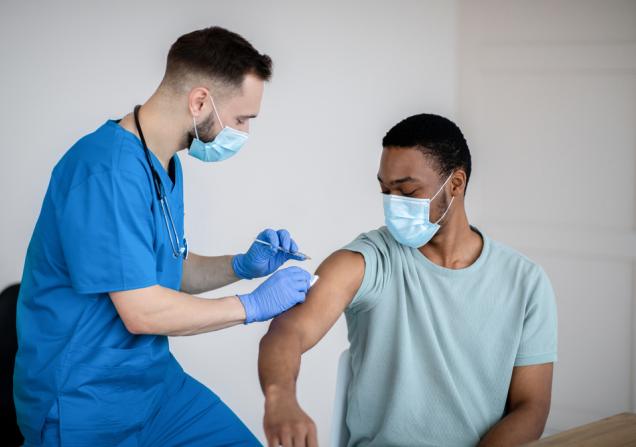 A doctor gives a man a COVID-19 vaccine. Image by Prostock studio via Shutterstock