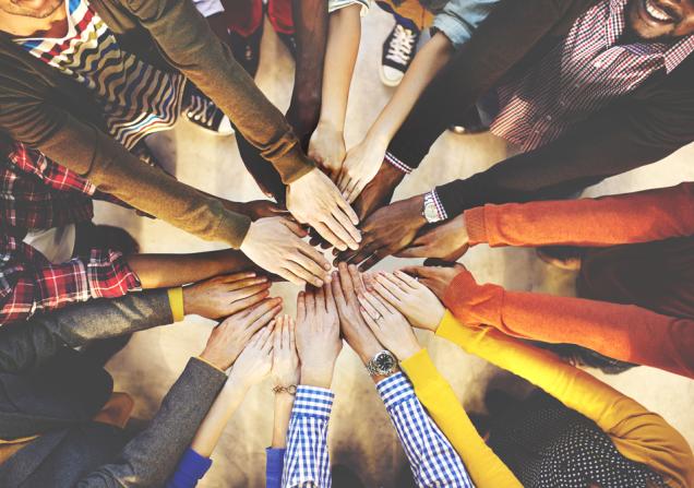 Multiple people's hands reaching together as viewed from above. Image by Rawpixel.com via Shutterstock