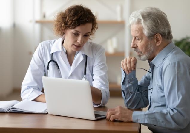 A doctor and senior patient looking at a laptop screen together. Image by fizkes via Shutterstock.