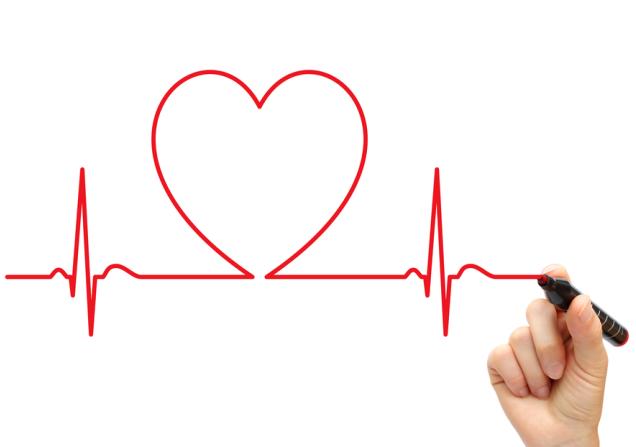 A person drawing an ECG style link with a red pen. Part of the line is shaped like a heart. Image by LeventeGyori via Shutterstock.