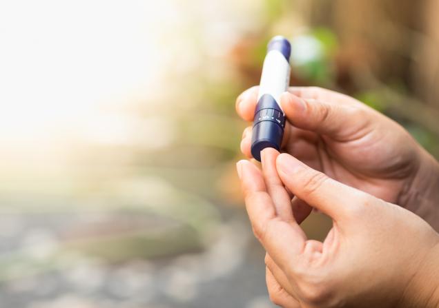 A woman pricks her finger to check her blood sugar levels. Image by Montri Thipsorn via Shutterstock.