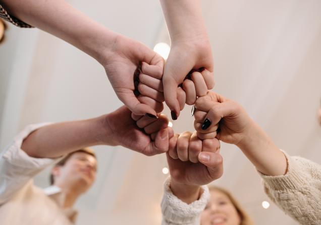 Five hands viewed from below doing a fist bump. Image by Pavel Danilyuk via Pexels.