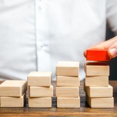 A man is building a ladder or growth chart from blocks. Strategy planning business expansion. Climbing the career ladder. Increase in income, organization of processors. Prioritization. Leadership 