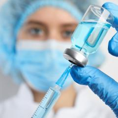 Doctor filling syringe with medication, closeup. Vaccination and immunization. Image by New Africa via Shutterstock