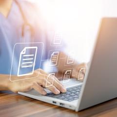 A doctor views treatment guidelines on a computer. Document icons float in the air.