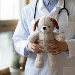 Healthcare professional in a white coat holding a plush toy dog