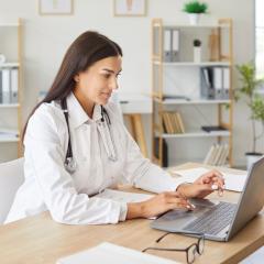 A doctor using a laptop. PATH will deliver AI tools to help improve cancer patient care.