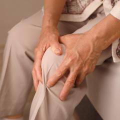 A woman holds her painful knee. We need research into osteoarthritis to develop new treatments.