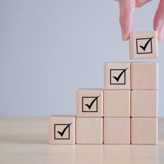 A set of wooden blocks, rising in height, with a tick at the top of each column to show regulatory approval of health research results.