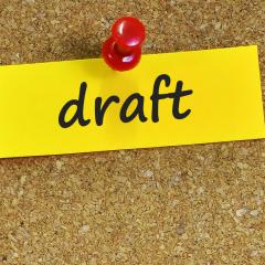 Draft written on yellow paper, pinned to a cork board, shows health research funding opportunities