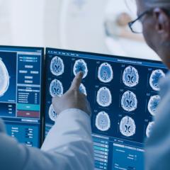 Medical staff discussing a brain scan on a computer screen. Image by Gorodenkoff via Shutterstock.
