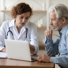 A doctor and senior patient looking at a laptop screen together. Image by fizkes via Shutterstock.