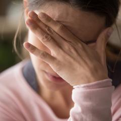 A woman holds her head in her hand. Image by fizkes via Shutterstock