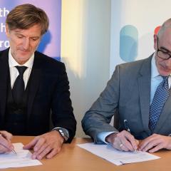 Jean-Marc Bourez, CEO of EIT Health, and Hugh Laverty, Executive Director ad interim of IHI JU, sign the Memorandum of Understanding. They are sitting next to each other at a table. Both are wearing suits and a tie. Image by IHI Programme Office.