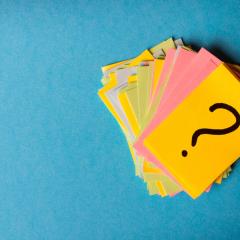 Image by SNeG17 via Shutterstock. A pile of pieces of yellow, green, blue and pink paper against a blue background. The top piece of paper is bright yellow and has a question mark on it. Image by SNeG17 via Shutterstock.