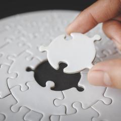 A person completing a jigsaw puzzle by placing the last piece in the centre. Image by Tinnakorn jorruang via Shutterstock.