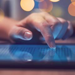 A close-up of a woman's hand scrolling on a tablet. Image by Bits And Splits via Shutterstock.