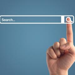 The index finger of a person clicking on a search button next to a search bar. Image by 19 Studio via Shutterstock.