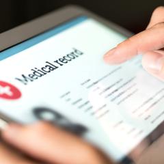 A close-up of a person holding a tablet. They are looking at their medical records. Image by Tero Vesalainen via Shutterstock.