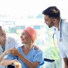 Woman with cancer speaking with doctors. Image by Nutnutchar NAV via Shutterstock.