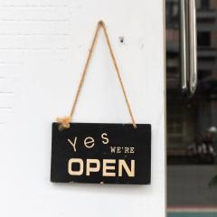 Sign hanging on a board that reads 'Yes we're open'. Image by Robbin Lee via Shutterstock